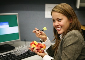 a pretty woman taking a break from the computer and eating fruit